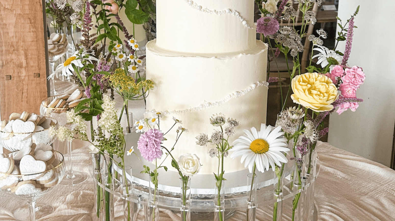 Garden party cake centrepiece styled on The Floral Crown platform stand with foliage for an outdoor marquee reception
