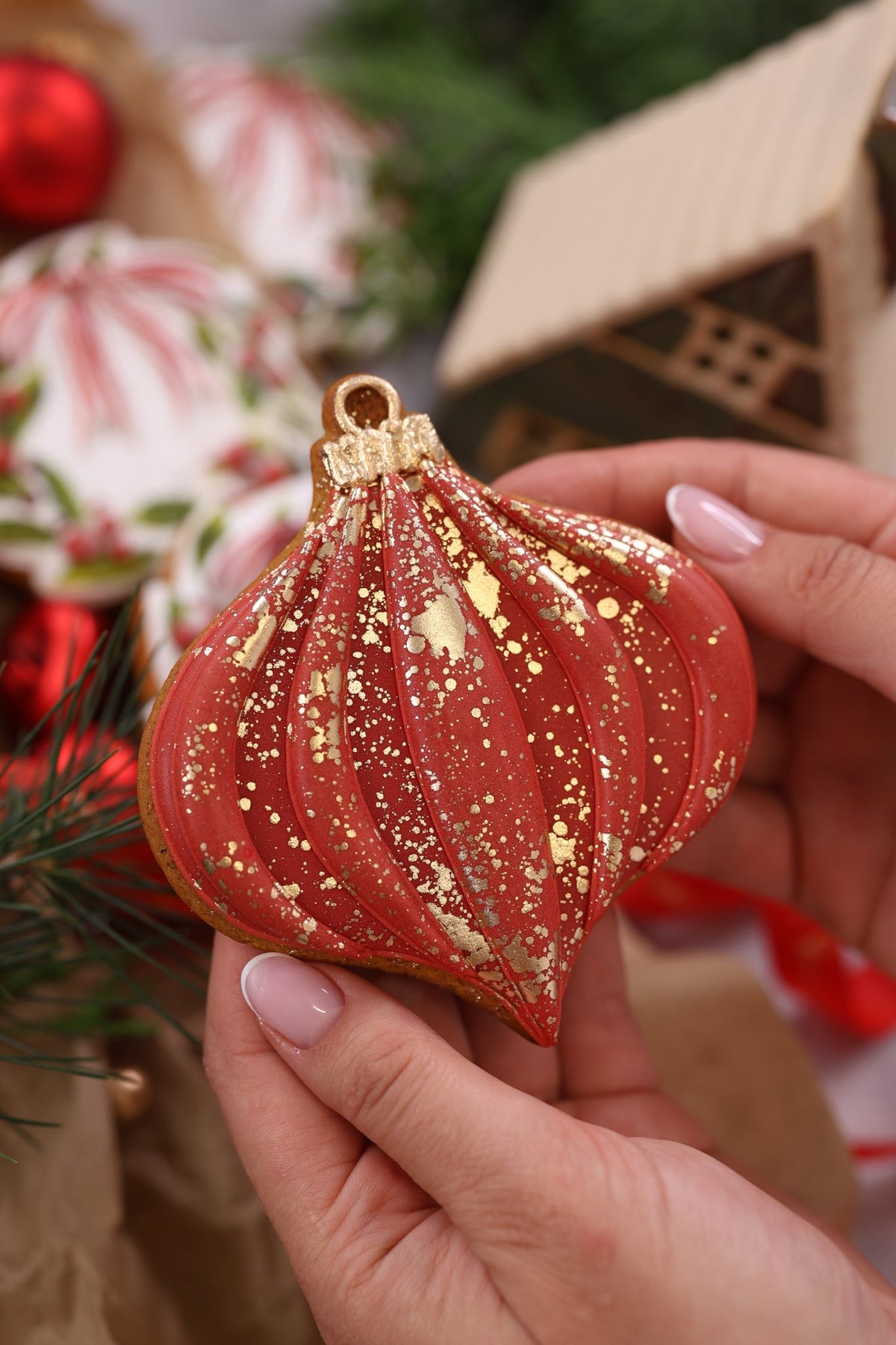 Red and gold bauble cookie held in hand